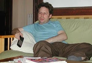 Man sitting on a couch, holding a TV remote