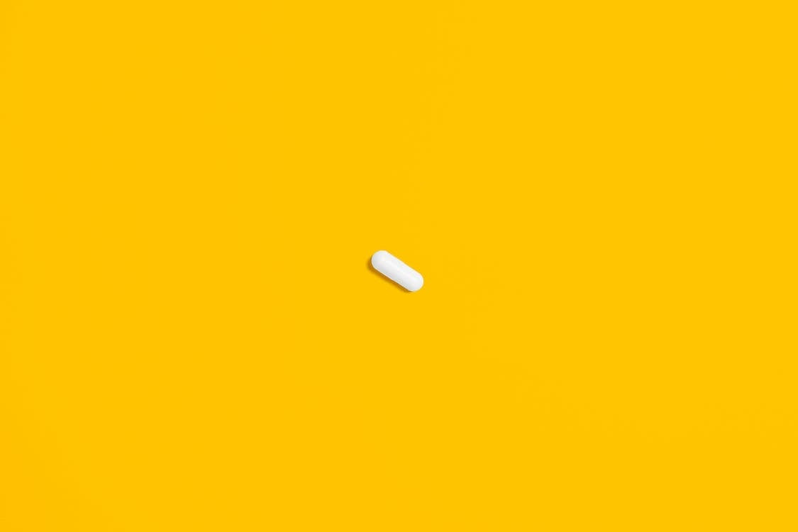 Free White Pill on Yellow Surface Stock Photo