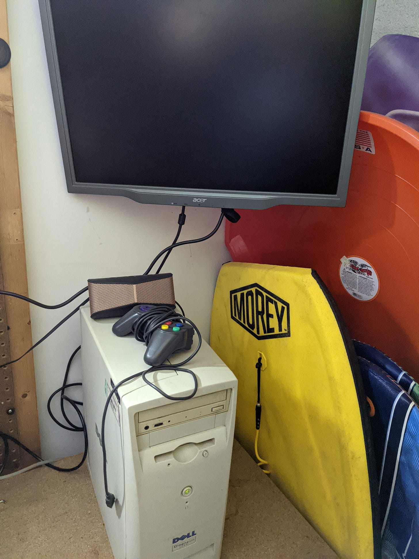 A Dell personal computer on a desk. A monitor is mounted on the wall behind it. A Dell personal computer on a desk. A monitor is mounted on the wall behind it.