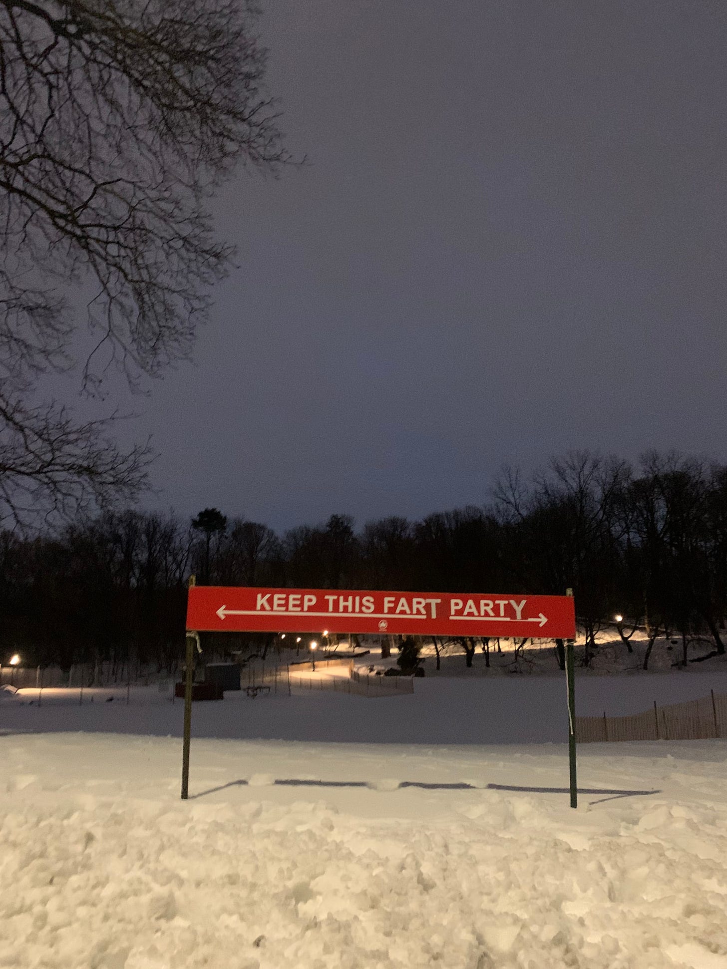 A sign in a snowy park changed from "Keep this far apart" to instead read "Keep this fart party"