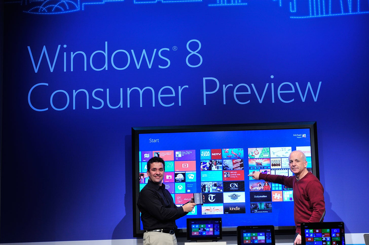Photos shows the 82" touch screen computer running windows 8. the background features a large "Windows 8 Consumer Preview" projection.