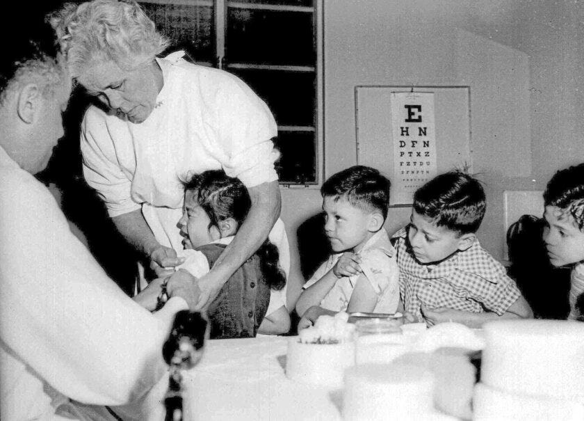 Black and white photo of a nurse administering polio vaccine in 1955