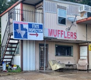 A state inspection sign hangs next to the words Mufflers at a mechanics shop on Westfield Drive in Aldine. 