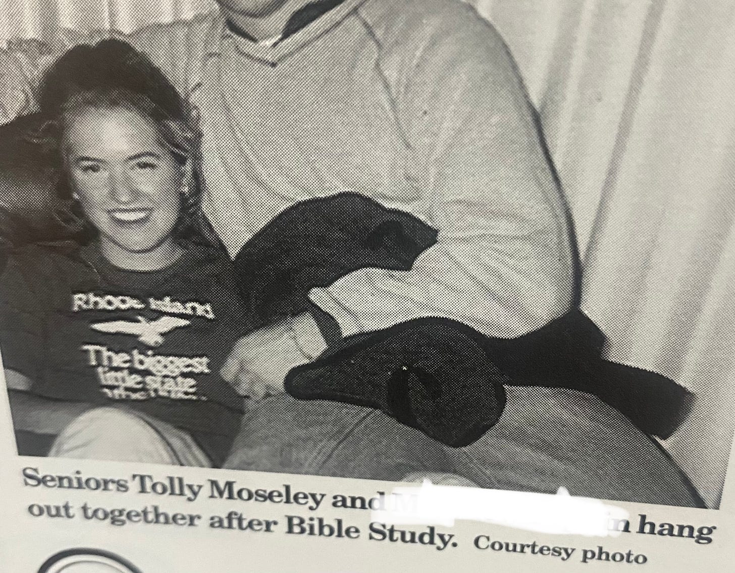 A newspaper clipping of young Tolly cuddled next to a boy on a couch with a caption "Seniors Tolly Mosele and [redacted] hang out together after Bible study.