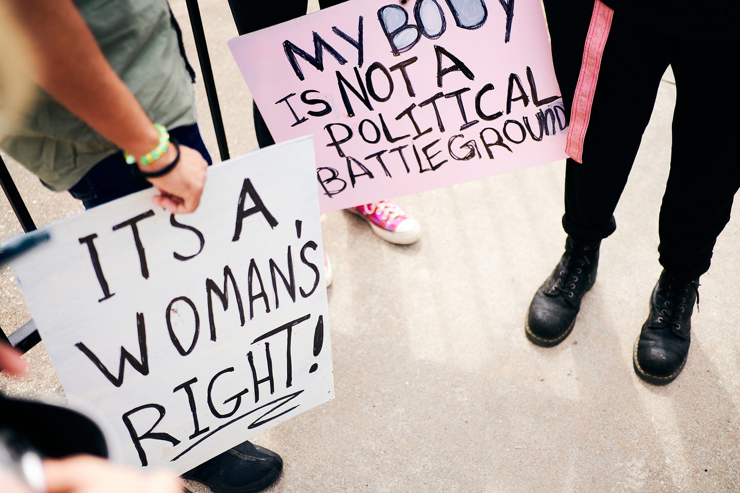 Photos of pro-choice signs: "It's a woman's right!" and "My body is not a political battleground"