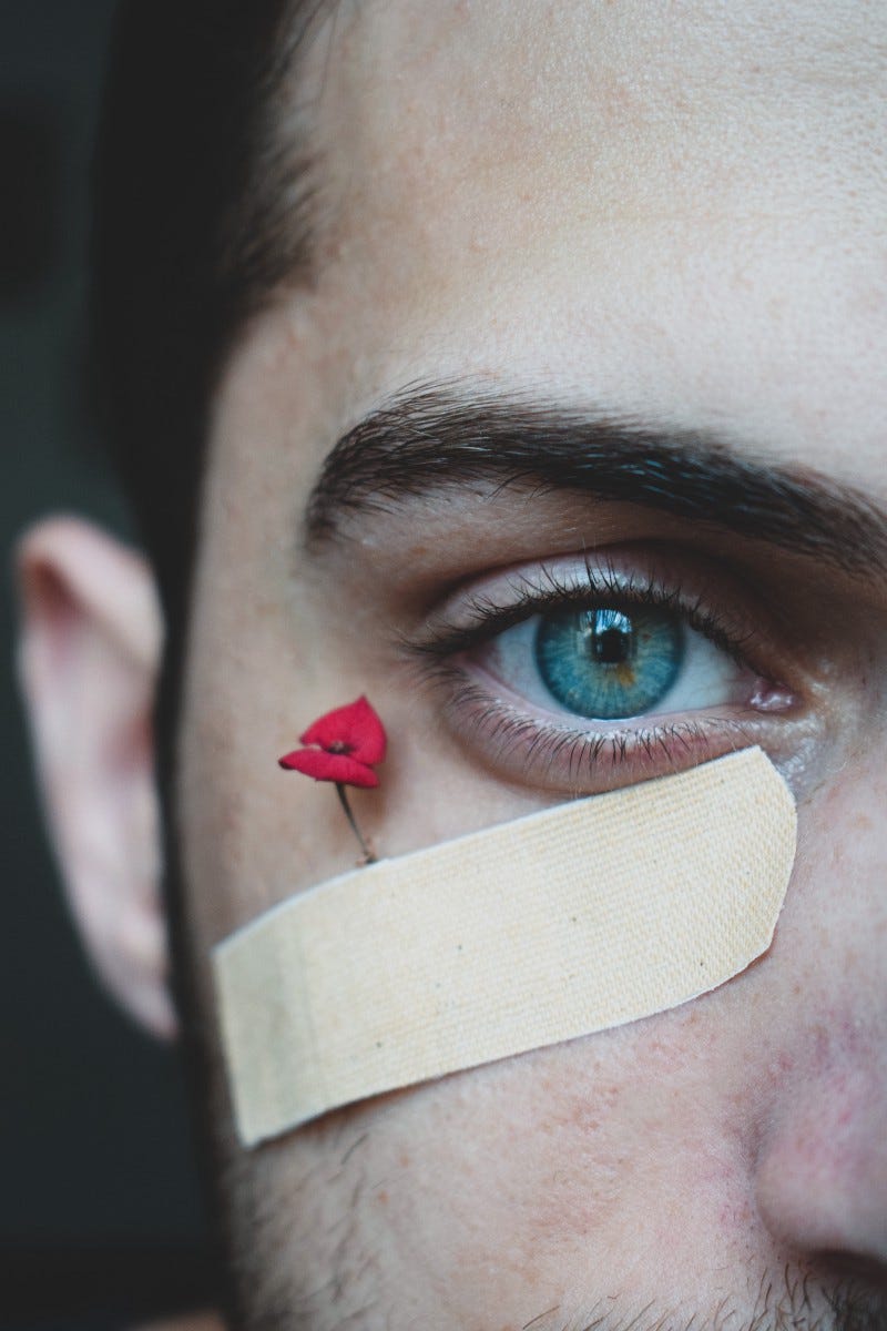 man with close up of one blue eye and band-aid tiny flower