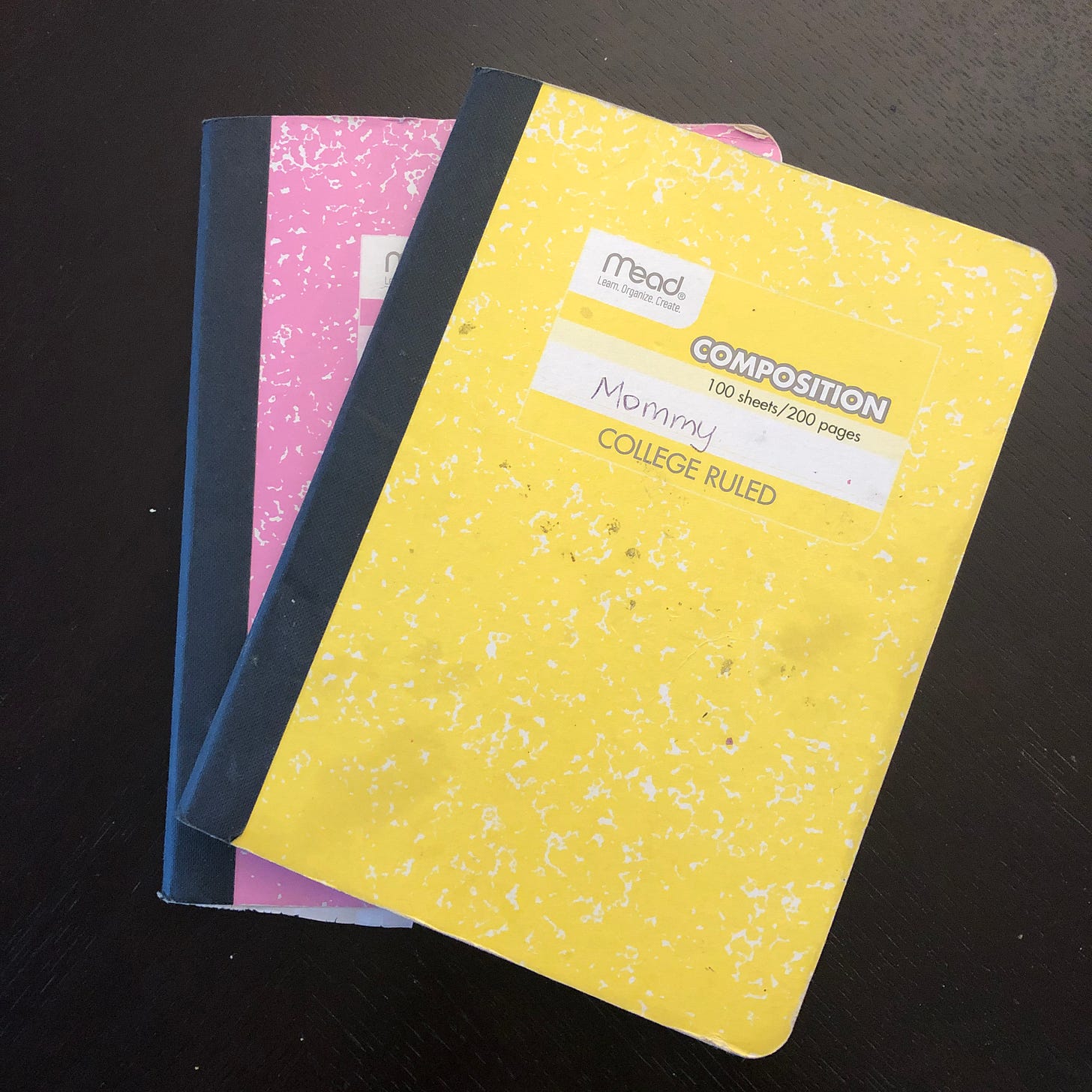 two composition notebooks, one pink and one yellow, labeled "Mommy"