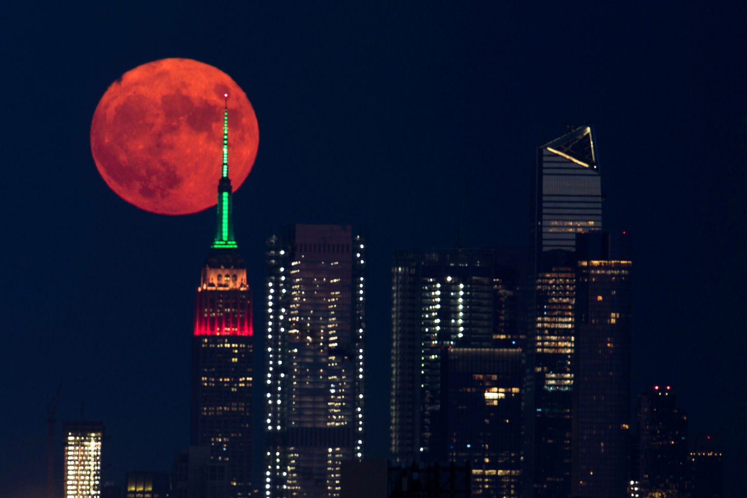 The full moon rises behind the Empire State Building in New York City, New York, U.S., July 23, 2021. REUTERS/Bjoern Kils/New York Media Boat 