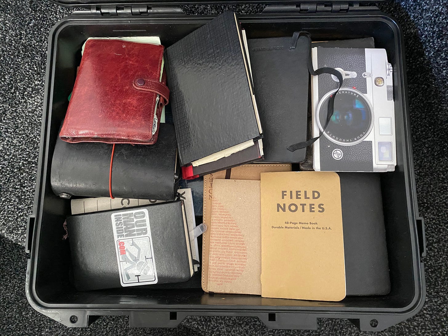 A plastic waterproof suitcase lies open filled with a variety of notebooks. Some leather, some field notes and some hardback.