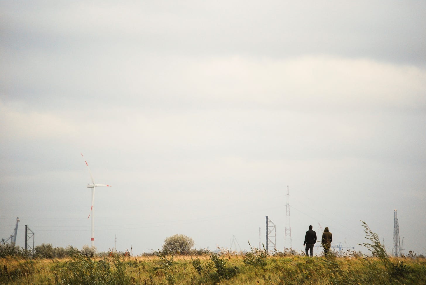 Two people walking in a field on a cloudy day.