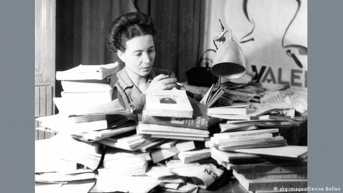 Simone de Beauvoir at a desk piled high with books 
