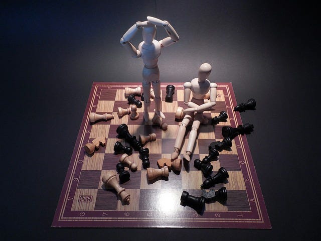 Stick figure knocking over chess pieces in frustration