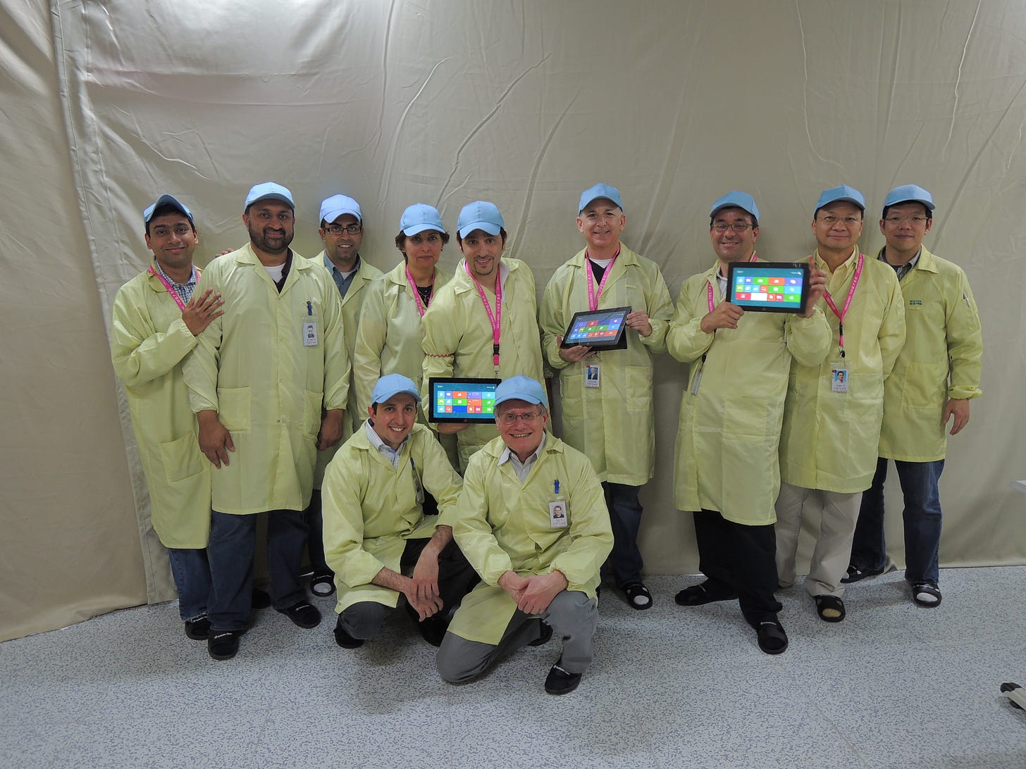 11 members of the team in protective gear posing for a photo at the factory.