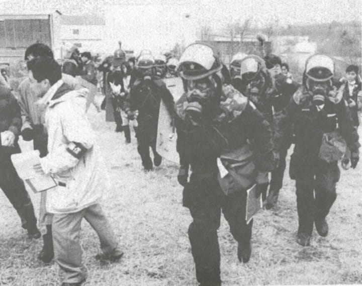 Personnel in gas masks evacuating Japanese people from the subway