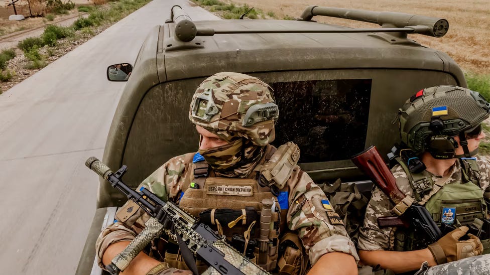 A photo of two Ukrainian soldiers riding in the back of a vehicle