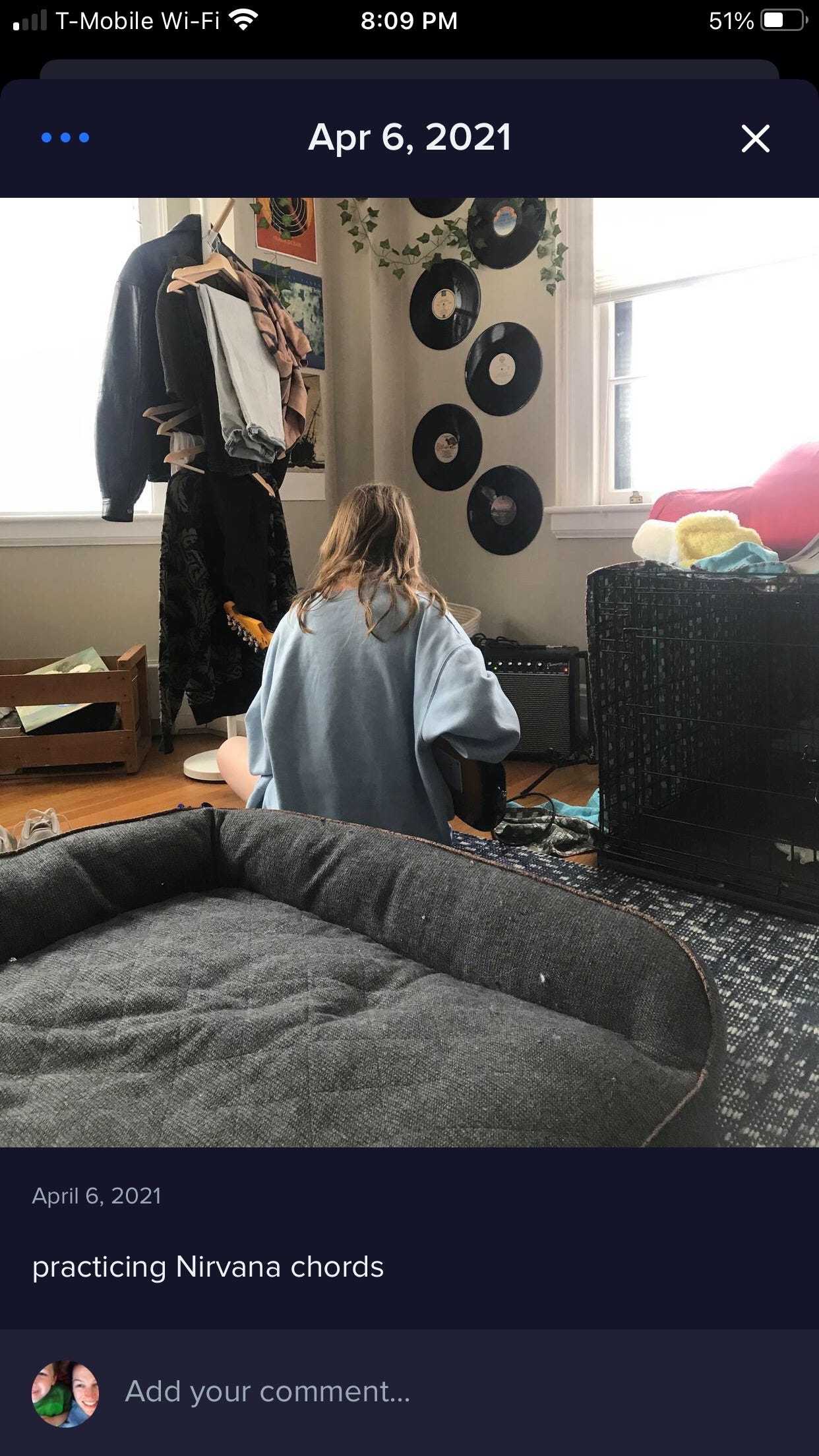 The Notabli app captures an image of a teenager, seated with her back to the camera, electric guitar in hand, surrounded by her messy room with dog bed, records on the walls, climbing vines, and articles of clothing.