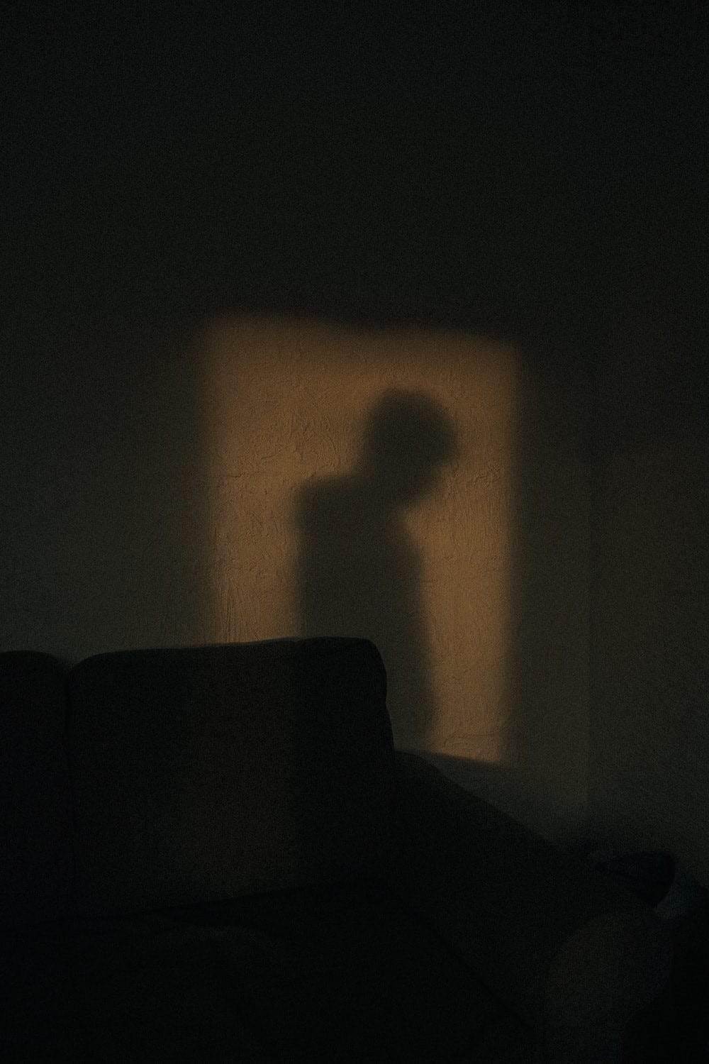A dark background with the shadow of a lonely looking figure