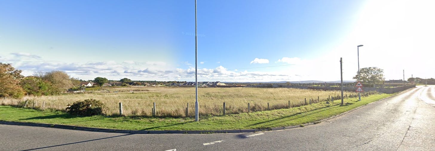 Image from Google Streetview of the site of the early medieval monastery of Kinneddar in Moray. It's a flat grassy field with a new housing estate encroaching on it from the east. 
