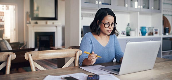 A woman sits at a desk, working. In her home