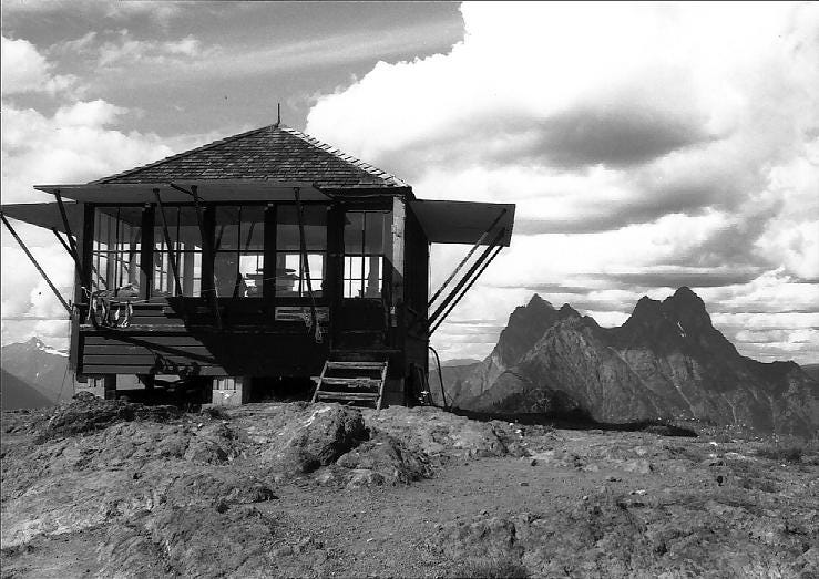 A small hut with big windows atop a mountain.