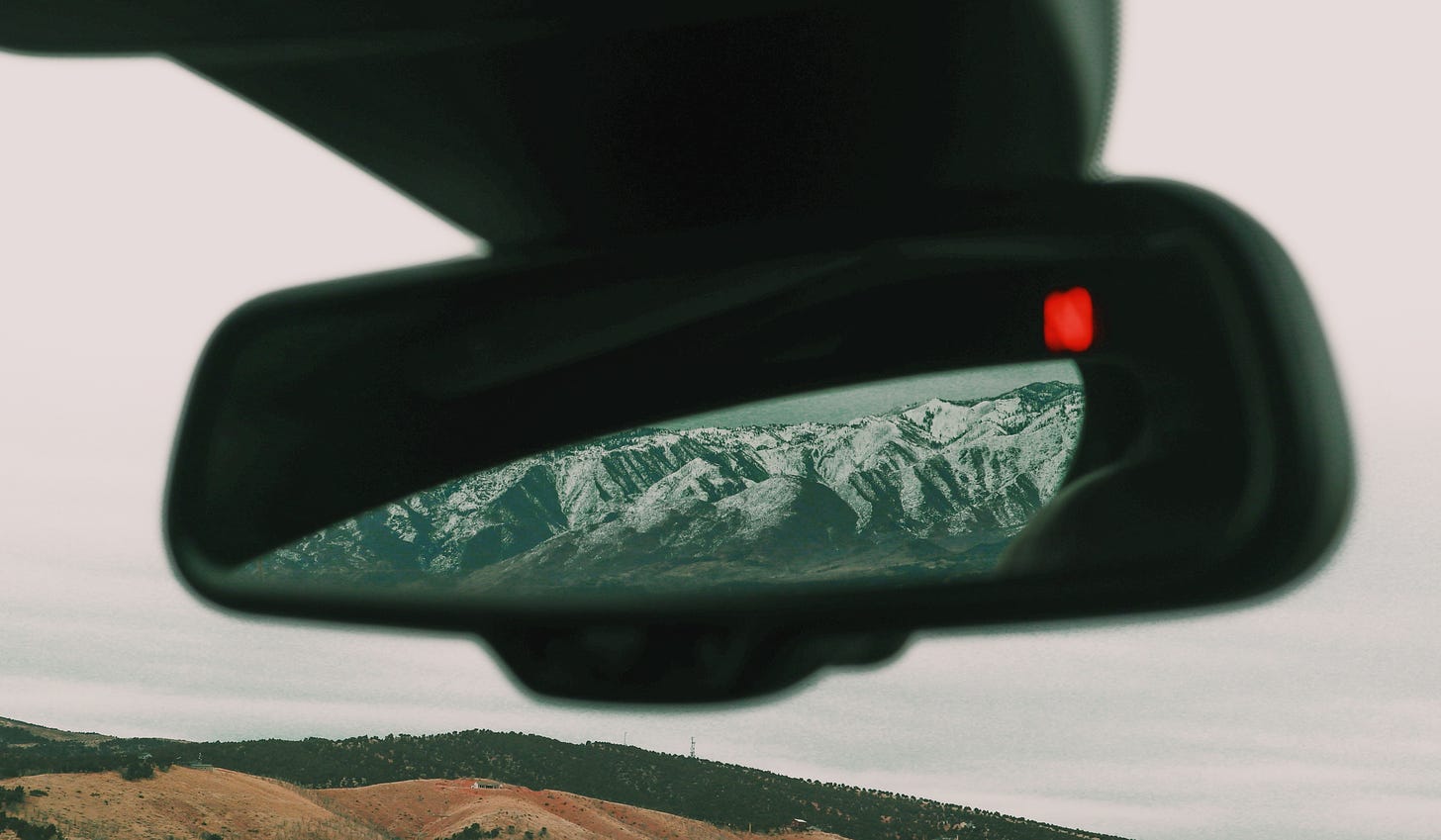 Free upsplash image of mountains reflected in a car rearview mirror. 
