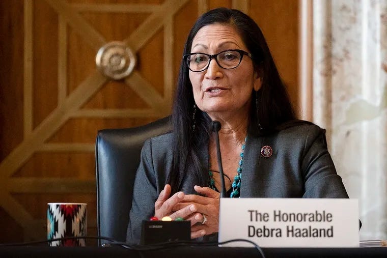 Interior Secretary Deb Haaland during a confirmation hearing. She is seated at a microphone with a coffee mug.