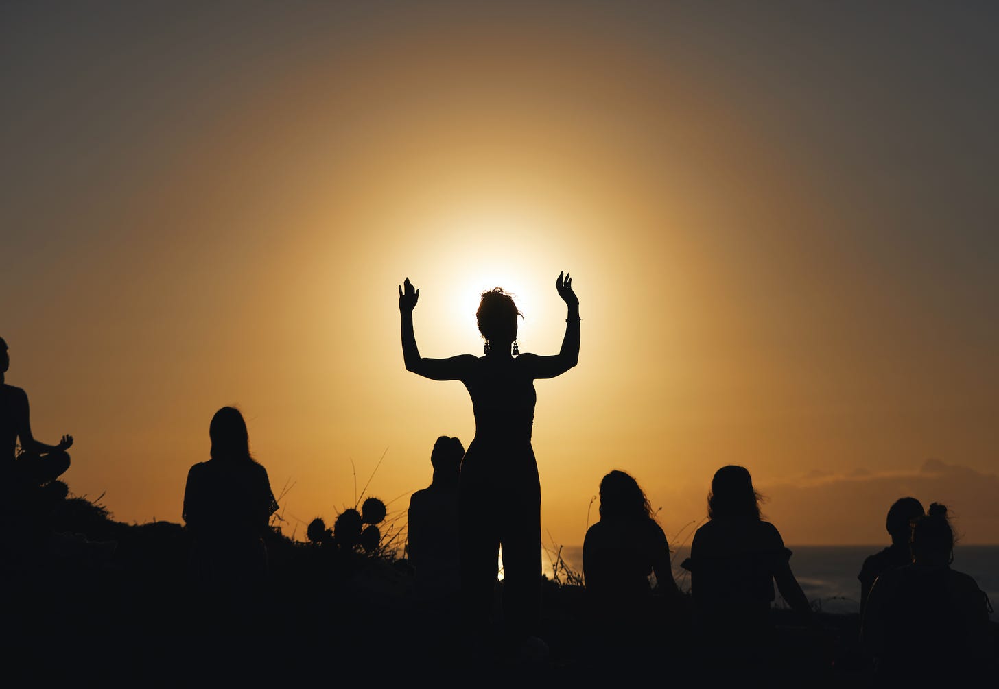 A silhouette of a person raising their hands up in front of a sunset

Description automatically generated with low confidence