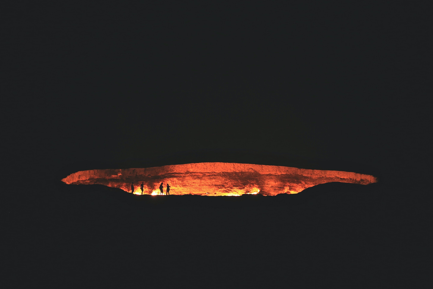 People near cave that is lit up by fire.