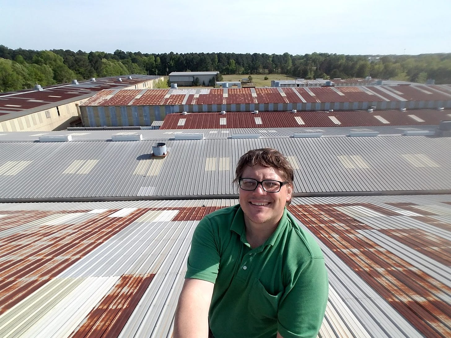 John Fenley poses on top of the roof of his massive compound
