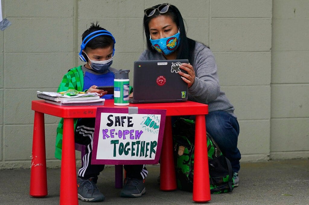 In this Thursday, Feb. 18, 2021, file photo, Maya Peralta, right, sits with her son, Clarendon Alternative Elementary School second-grader H Suchovsky, as students and parents attend distance learning Zoom classes at Midtown Terrace Playground in San Francisco. (AP Photo/Jeff Chiu, File)