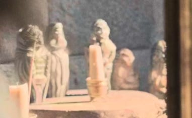 A row of five stone figures, pale in the daylight