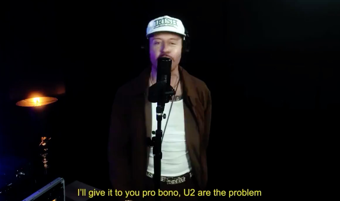 Macklemore video clip with subtitle "I'll give it to you pro bono, U2 are the problem"