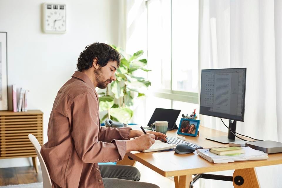 Male Freelancer Writing In Book At Home Office