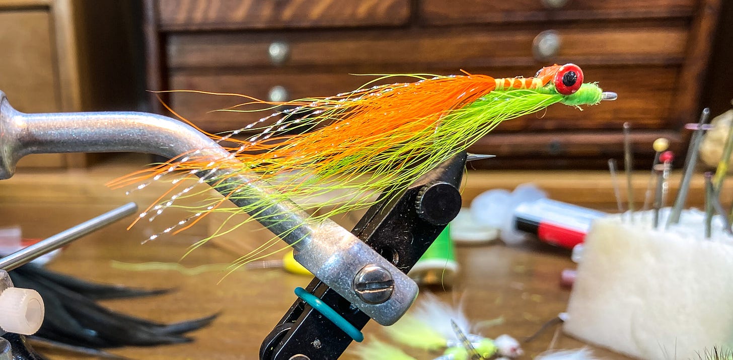 Pumpkin and chartreuse Clouser minnow in a rotary vice. [Photo: Dean Shadley]