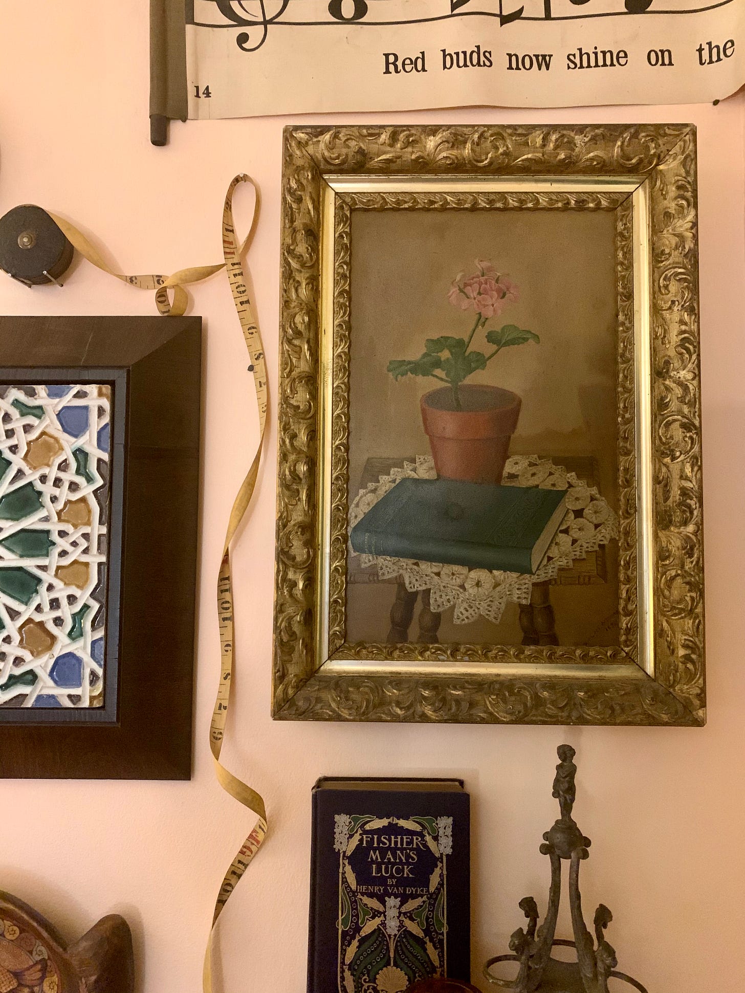 a painting of a begonia and a blue book in a gold gesso frame