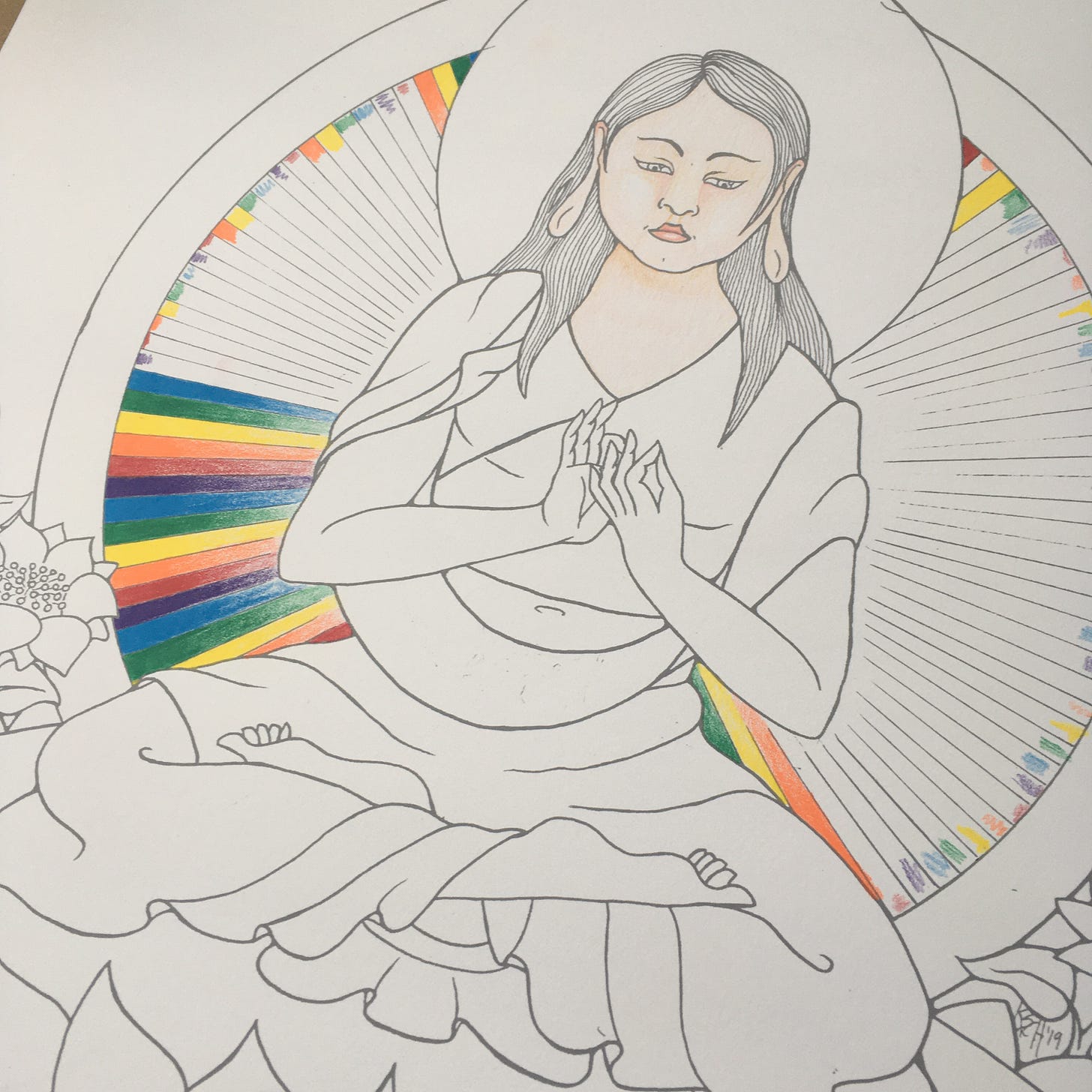 Photo of the progress of colouring in the radiance lines behind a drawing of the Buddha Vairochana. Vairochana is depicted as a soft, round Korean woman with long hair just passed shoulder length, sitting cross-legged with her hands in the bodhyagri mudra.