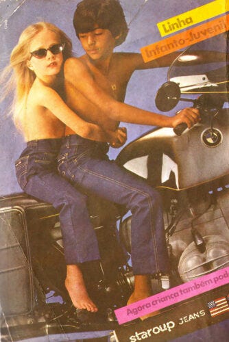 propaganda da staroup jeans lançando a linha infanto-juvenil mostrando um menino montado em uma moto, com uma menina de óculos escuros e cabelos loiros longos, agarrada a ele na garupa. os dois estão sem camisa, só de jeans, em uma pose extremamente sexualizada