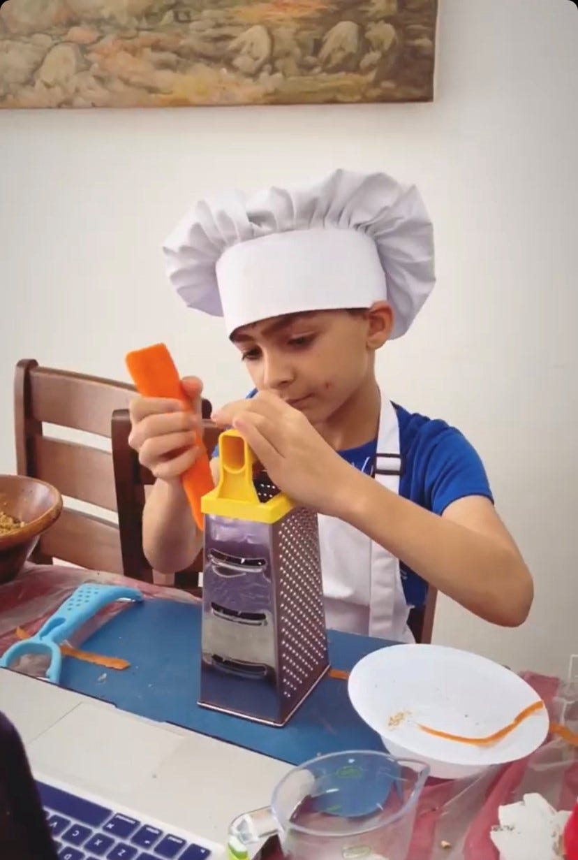 A kid learning to grate carrots with a live, online lesson from upiopi