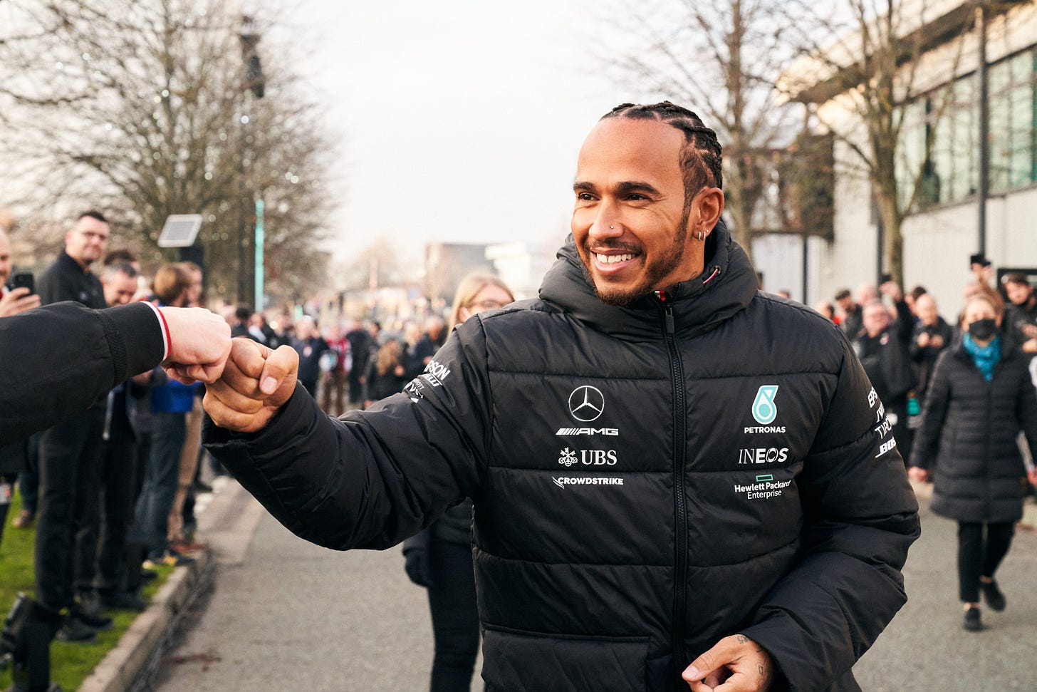 lewis hamilton fist bumping a colleague as he walks down the road