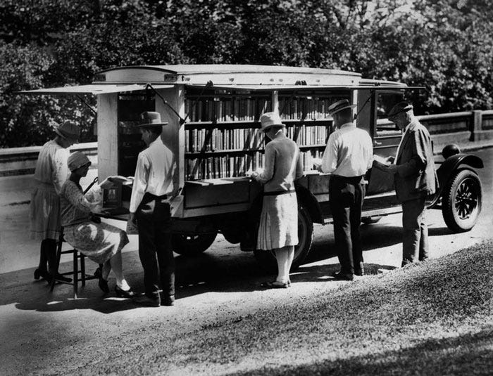 People stand around a truck with books, browsing