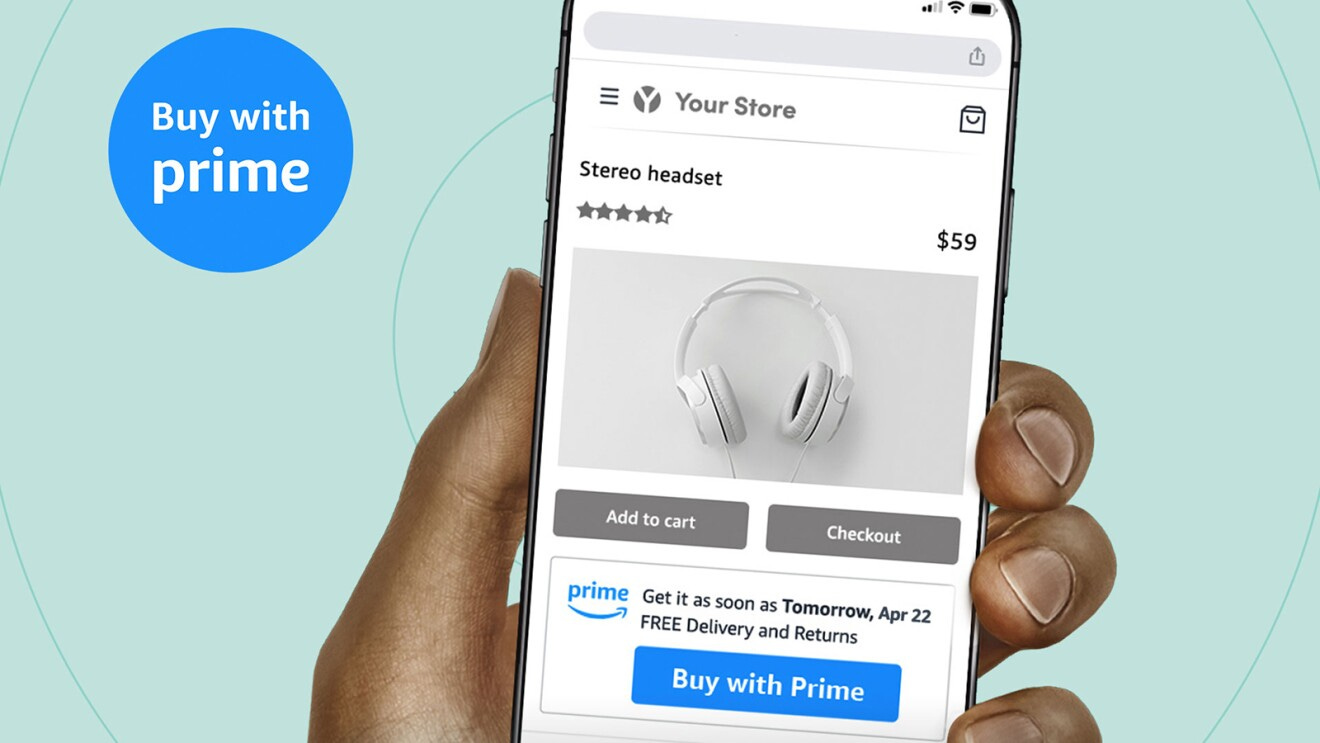 A hand holding a phone with Amazon's "Buy it with Prime" feature on the screen. Someone is buying headphones with the new feature. There is a blue text bubble on the left side of the screen that says "Buy it with Prime."