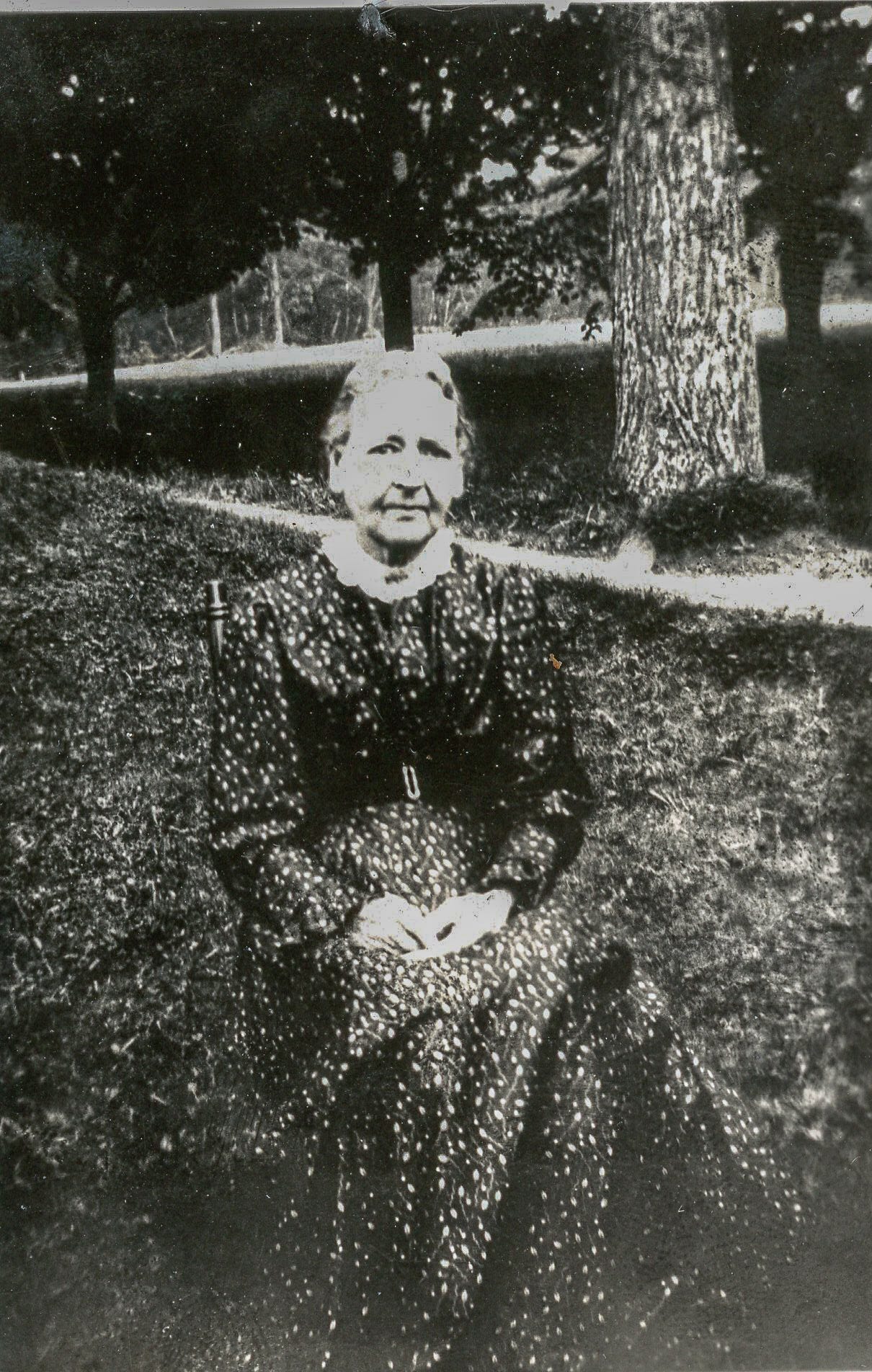 Woman in dress seated on a chair outside