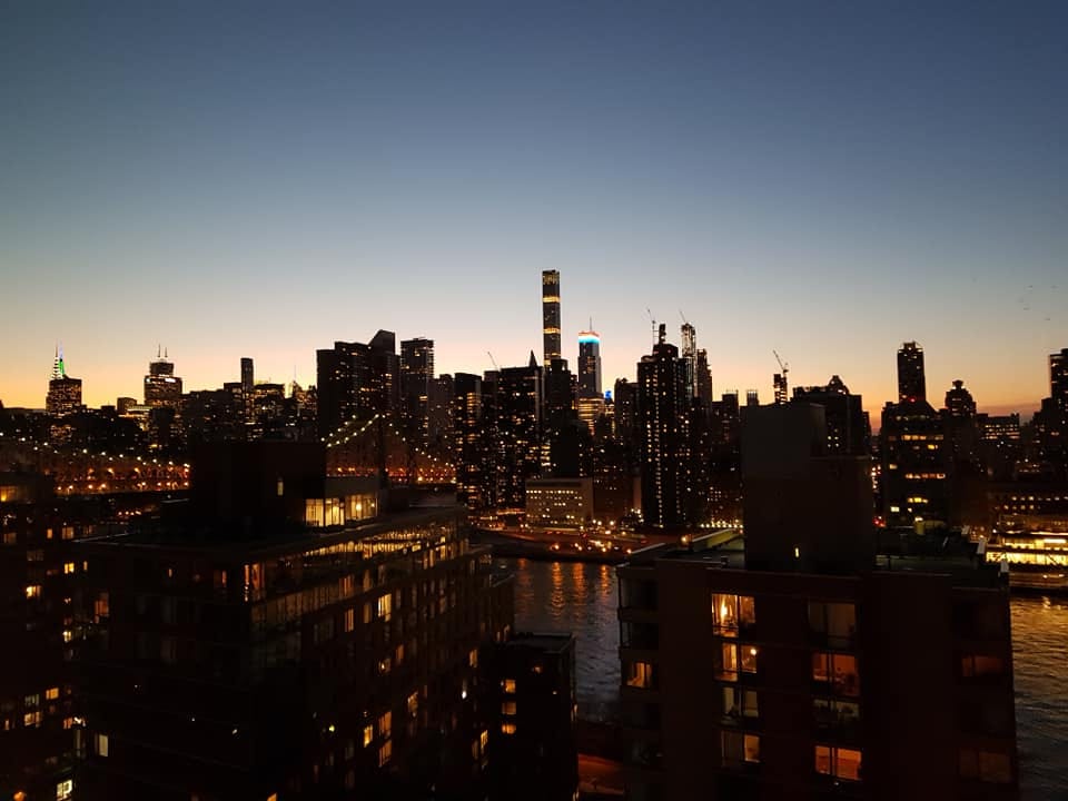 En silhuett av skyskrapor med ljusa fönster mot en mörknande kvällshimmel.
