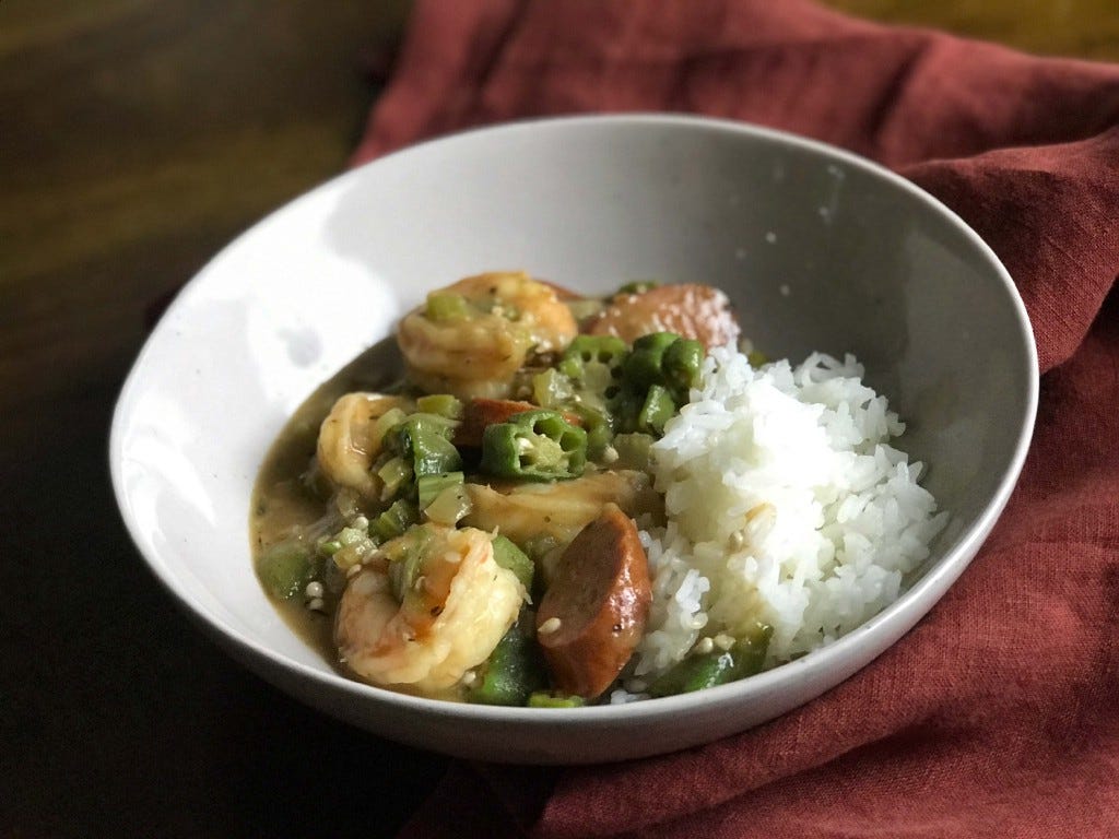 Shrimp, andouille sausage and okra gumbo with white rice, served in a white bowl. The recipe is from Cooks Without Borders.