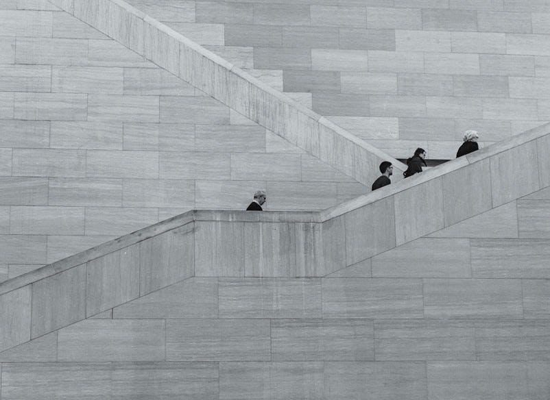 four people going up grey stairs