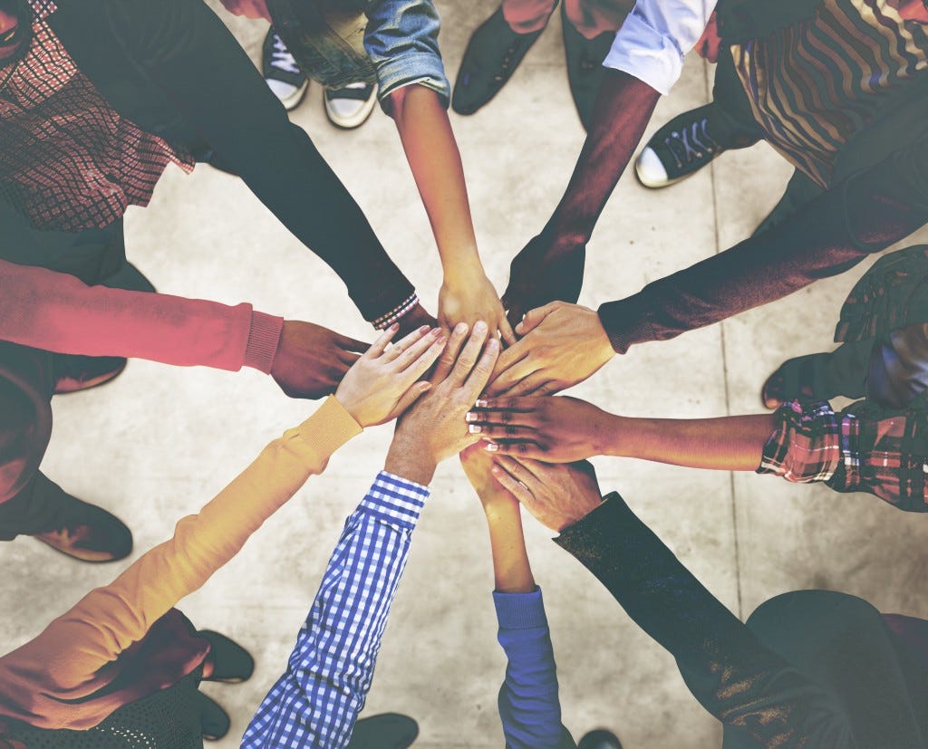 diverse hands outstretched into the center of a circle of people showing unity