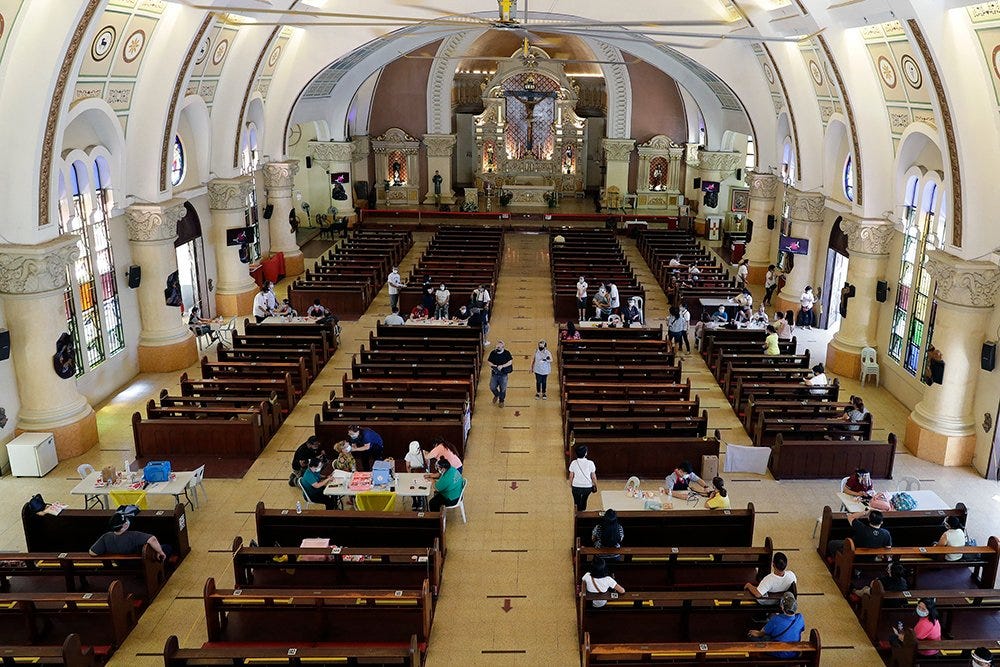 Health workers inoculate residents with the AstraZeneca COVID-19 vaccine inside the Sacred Heart of Jesus Parish church in Quezon City, Philippines, on Monday, May 17, 2021. The church was used to speed up the vaccination process to residents in the area. (AP Photo/Aaron Favila)