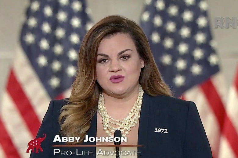 Abby Johnson stands behind a podium in front of a line of American flags while speaking at the RNC.