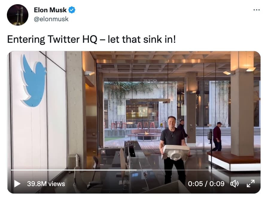 Tweet from Elon Musk reading, "Entering Twitter HQ - let that sink in!" as he carries a porcelain sink into the building