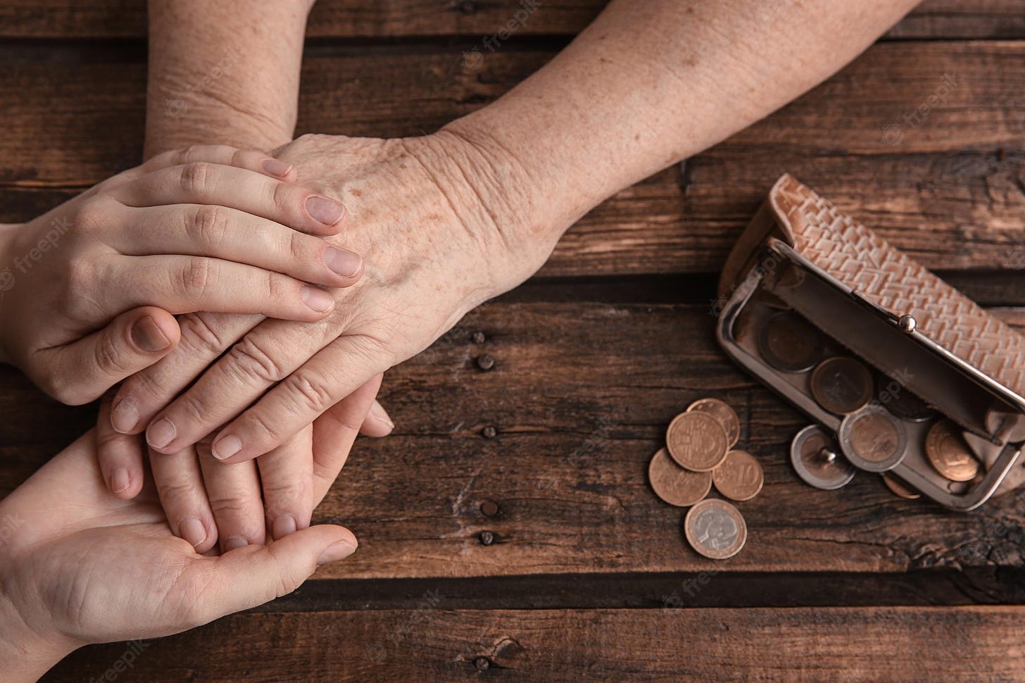 Premium Photo | Hands of young and elderly woman and purse with coins on  wooden background. poverty concept